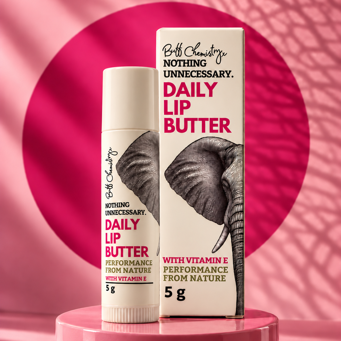 A Lip Butter Tube and box of Buff Chemistry 'Nothing Unnecessary' Daily Lip Butter, featuring a black and white elephant graphic on a white background with bold pink text.