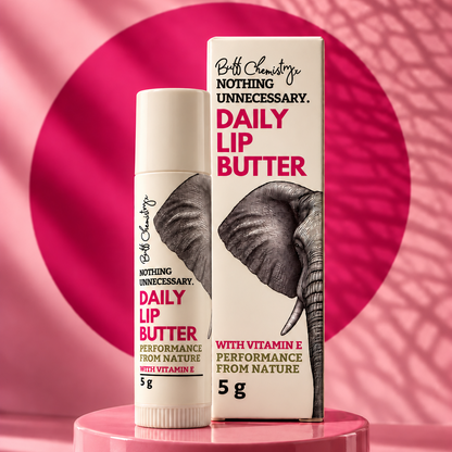 A Lip Butter Tube and box of Buff Chemistry 'Nothing Unnecessary' Daily Lip Butter, featuring a black and white elephant graphic on a white background with bold pink text.